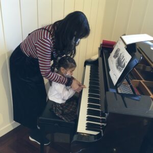 先生と一緒にグランドピアノで曲を弾く練習をしました。