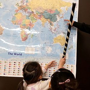 大きな世界地図で日本の位置を確認する生徒