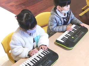 親指をドに合わせピアノを弾く生徒たち