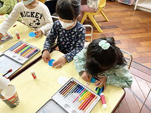 人形の顔を色鉛筆で描く子どもたち