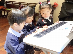 お友だちと並んで電子ピアノを弾く生徒たち