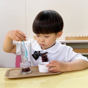 別の容器に豆を移す生徒