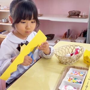 真剣な表情でハサミで紙を切る生徒