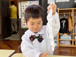 長く繋いだ洗濯ばさみを持ち上げて嬉しそうに微笑む生徒