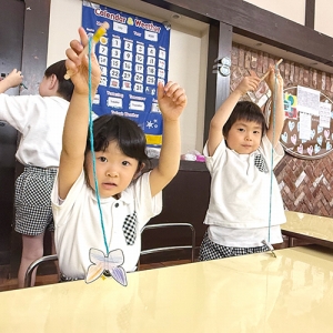 磁石付きの糸を付けた棒でちょうちょを吊り上げる生徒たち