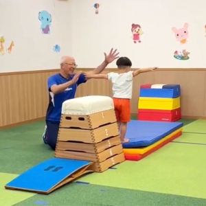 跳び箱を跳んでポーズを決める生徒と一緒に喜ぶ先生