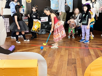 ハロウィーンパーティーのパンプキンゴルフを楽しむ子ども