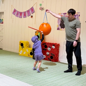 先生が持ち上げるピニャータを割ろうと棒を振り上げる生徒