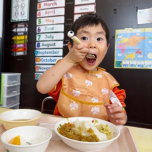 大きな口でカレーライスを頬張る生徒