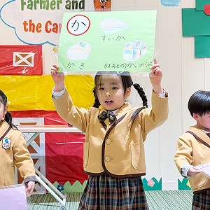 大きな画用紙を頭上に掲げてひらがなの発表をする生徒