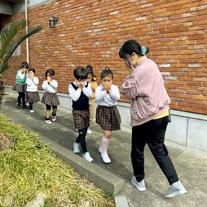口を手で押さえて避難をする先生と生徒たち