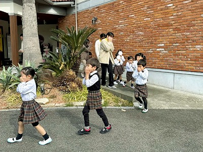 口を手で押さえて避難をする先生と生徒たち