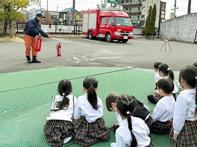 消防士さんに消火器の使い方を教わる生徒たち