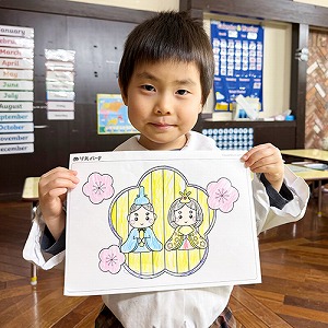 完成したひなまつりの塗り絵を見せる生徒