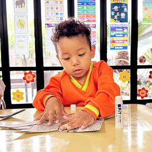 新聞紙かぶとにのりを塗る子ども