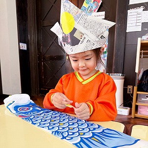 かぶとを被りこいのぼりを制作する生徒