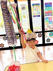 新聞紙かぶとを被りこいのぼりを掲げる生徒