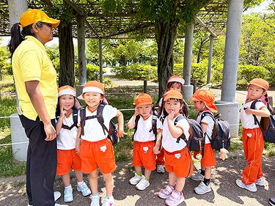 お友だちと手を繋いで歩く生徒たちと引率する先生