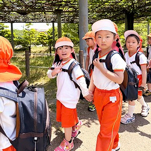 リュックサックを背負ってお友だちと手を繋いで歩く生徒たち