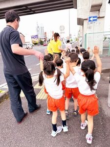 手を上げて道路を渡る生徒たちと先生