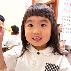 箸でつかんで笑顔を見せる生徒