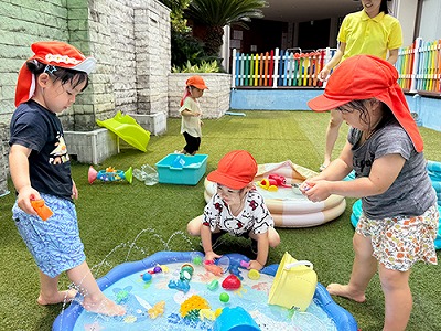 プールの周りで水遊びをする子どもたち