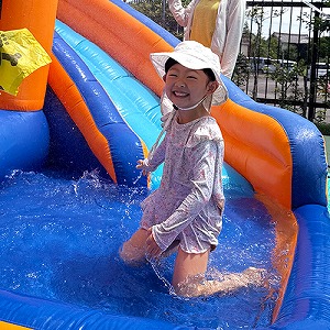 プールの滑り台を滑って笑顔を見せる生徒