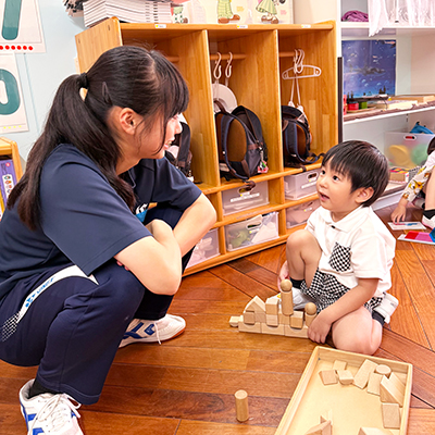 キンダースクールの生徒と積み木をする中学生