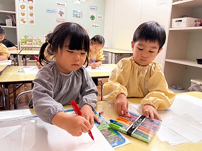 風車に熱心に色を塗る子どもたち