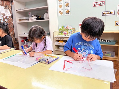 風車に熱心に色を塗る子どもたち