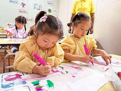 風車に熱心に色を塗る子どもたち