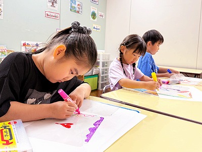 風車に熱心に色を塗る子どもたち