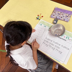 おはじきを使い英語で数字をかぞえながら足し算を考える生徒