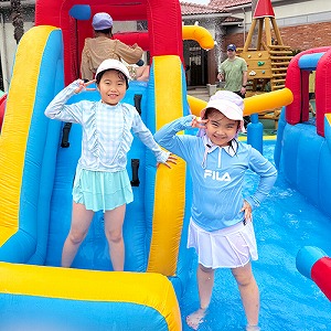 プールの滑り台の前でおともだちと一緒にポーズを決める生徒たち